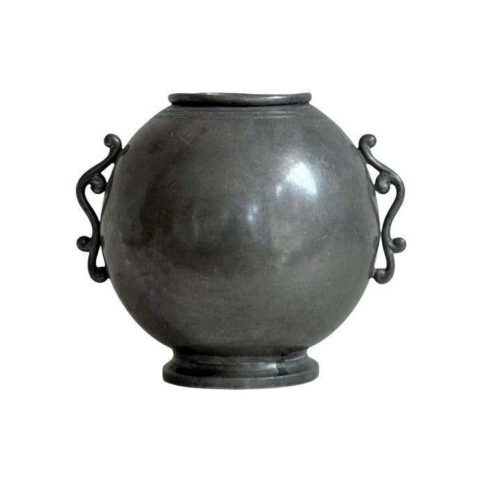 Round pewter vase with decorative scrolled wing handles and footed base