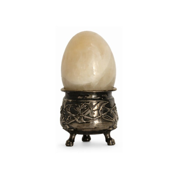 Marble egg resting in an ornate silver holder with decorative feet and floral relief detailing